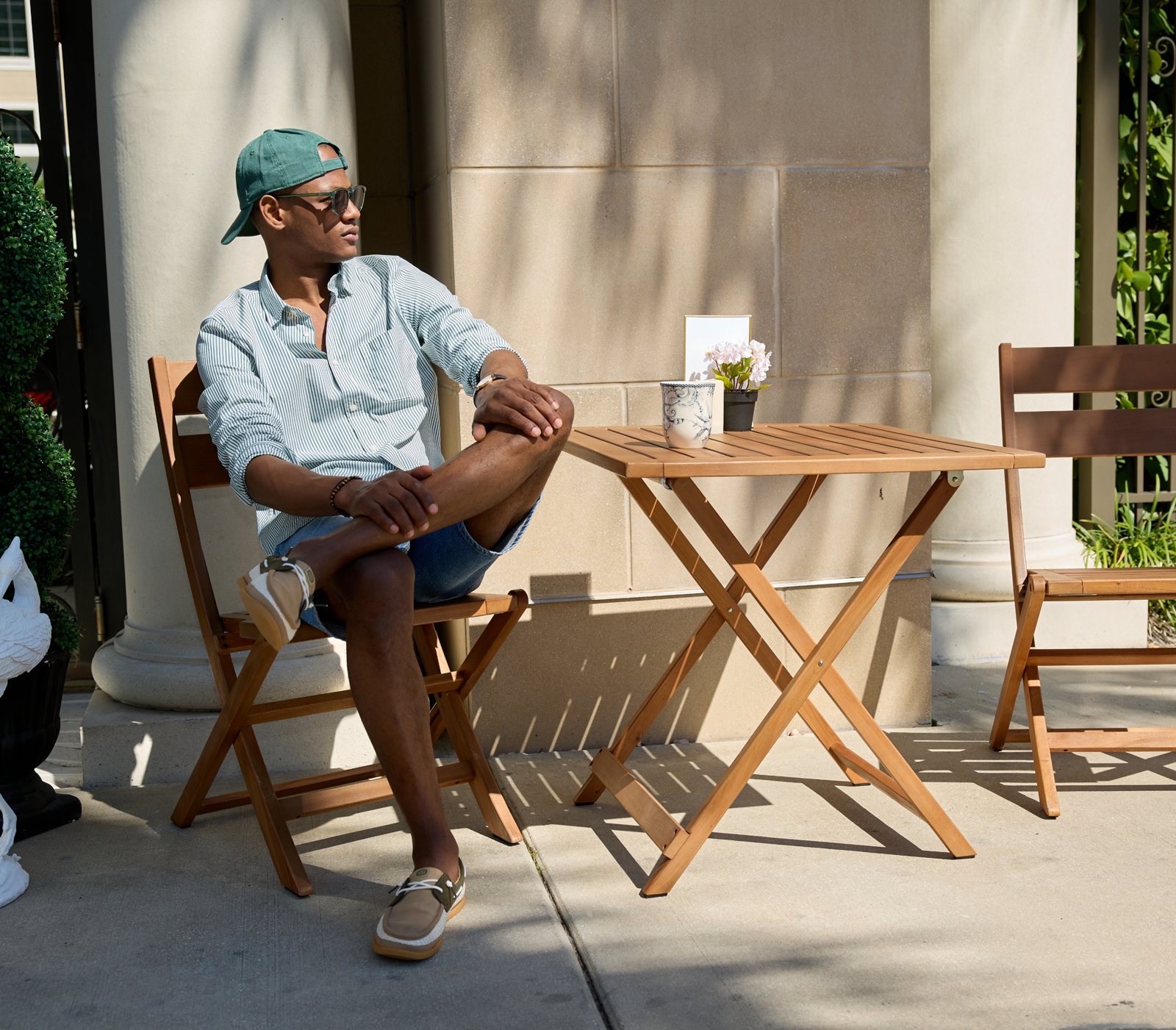 A man in HEYDUDE slip-ons, sitting at a café table in the sun